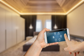 Woman holding smartphone with launched security program on blurred bedroom background