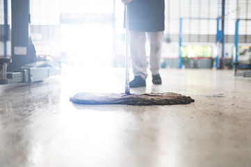 mechanic in auto repair center Cleaning using a mop Squeeze water from the epoxy floor. in the car...