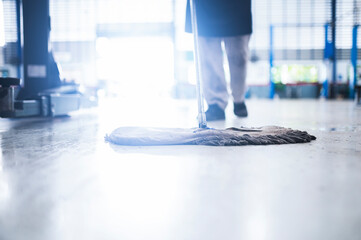 mechanic in auto repair center Cleaning using a mop Squeeze water from the epoxy floor. in the car repair service center