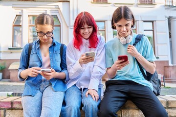 Teenage friends together outdoor having fun using smartphones