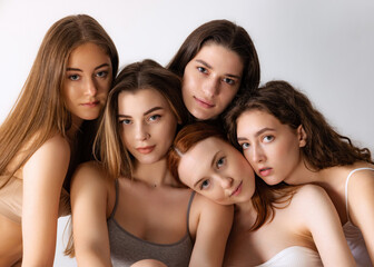 Portrait of beautiful young women with nude makeup posing, looking at camera isolated over grey...