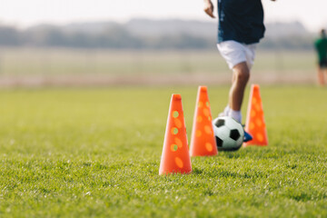 Children football player with training cones. Soccer agility training equipment. Kids playing sports on grass field. Happy boys practice sports. Kids football speed training drill