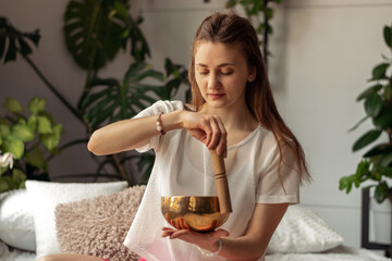 Young woman playing on a singing tibetian bowl.Relaxation and meditation.Sound therapy,alternative...