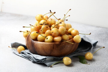 Ripe yellow cherries in a brown wooden bowl