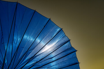 Selective focus of part of blue umbrella on isolated sky background. Warm weather, blue, protection idea.