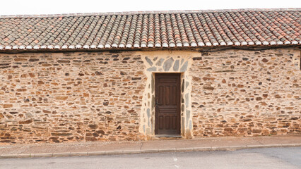 Puerta de madera en casa rural de piedra y estuco