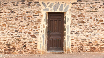 Puerta de madera en casa rural de piedra y estuco