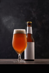 Bottle and glass of beer on black background.