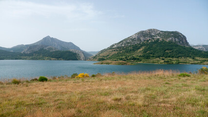 Lago rodeado de montañas rocosas y praderas de hierba
