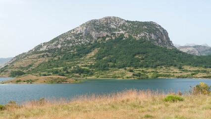 Fototapeta na wymiar Lago rodeado de montañas rocosas y praderas de hierba