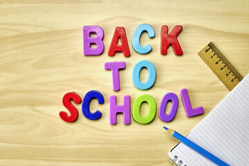 the phrase back to school is laid out in multicolored letters on the table next to a pencil ruler and a notebook with the concept of education school