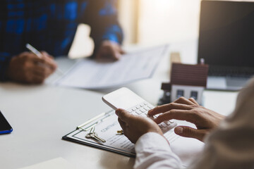 Real estate agents are discussing a mortgage on a house, land plot and calculating interest on a...