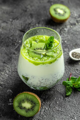Healthy breakfast chia pudding with kiwi in glass jars on a white table. Clean eating, dieting, vegan food concept. vertical image
