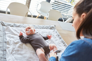 Baby liegt im Strampelanzug auf dem Wickeltisch