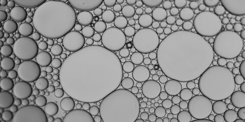 Oil and water bubbles of different sizes air bubble an attractive pattern with grey-silver gradient lighting effect to create an art image background.