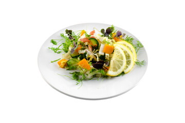 Vegetable salad with greens and pumpkin on a white plate on an isolated background, bright summer vegetables