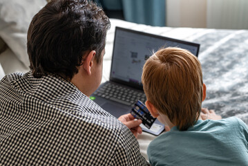 Young father and son shopping online together, family time. Child red-haired boy and dad at the...