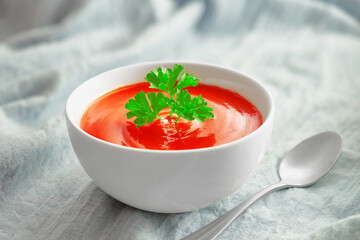 Close up bowl of tomato soup with parsley and spoon