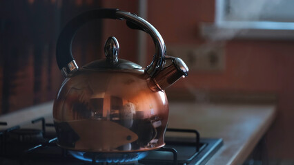 Close up of steaming tea kettle. Concept. Heater glowing under the steel polished kettle with...