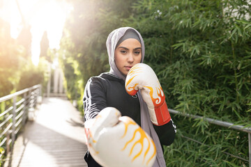 Arab female athlete of islamic faith practicing boxing outdoors - muslim woman practicing boxing -