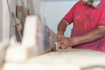 Latin carpenter with a mask working with wood, close-up.