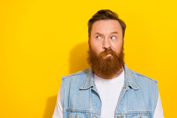 Photo of doubtful unsure man wear jeans waistcoat looking empty space isolated yellow color background