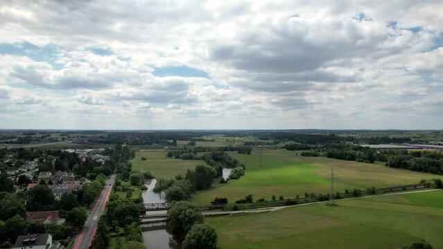The drone flies over a rural landscape over the river Regnitz and the suburb of Erlangen-Bruck
