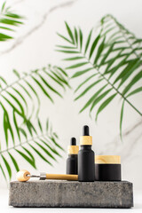 Concrete black podium for cosmetic products close-up among tropical leaves against the background...