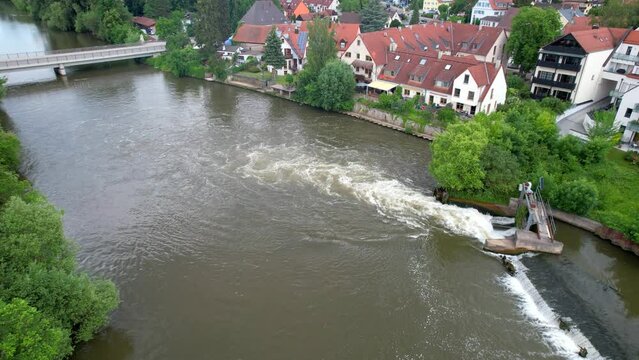 Drone footage of water running through a barrier  at the river Regnitz and the suburb of Erlangen-Bruck
