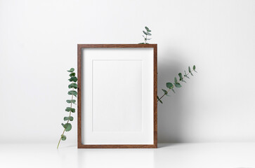 Vertical frame mockup in white minimalistic interior with eucalyptus plant decoration