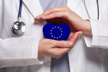 EU doctor holding heart with flag of European Union background. Healthcare, charity, insurance and medicine concept - obrazy, fototapety, plakaty