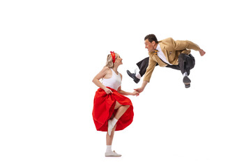 Dynamic portrait of dancing couple in vintage style clothes dancing, jumping isolated on white...