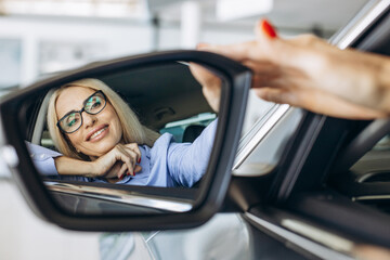 Fototapeta na wymiar Aged woman sitting in car in a car showroom