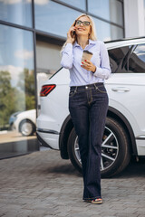 Fototapeta na wymiar Business woman drinking coffee and talking on the phone by the car showroom