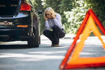 Woman standing by the car because of break down