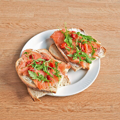Plate with a salmon sandwich on wooden table