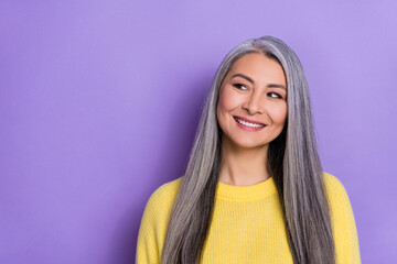 Photo of dreamy shiny lady pensioner dressed yellow pullover looking empty space isolated purple color background