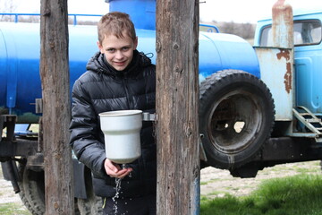 Life in the village. A boy washes his hands on the street in the village.