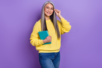 Photo of cute smart retired woman wear sweater hand eyeglasses holding book isolated violet color background