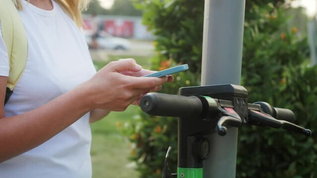 Tourist girl takes e scooter in sharing parking, tourist phone application. Eco transport. Friendly transportation methods.