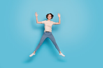 Full length photo of charming funny lady dressed beige t-shirt jumping up empty space isolated blue color background