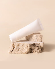 White plastic cream tube on stone on light yellow close up, Mockup