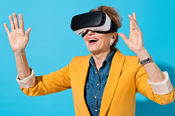 Mature woman with modern VR goggles. Photo of business woman in yellow blazer on blue background