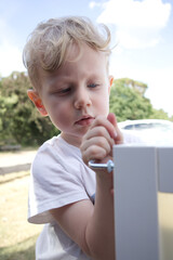 little boy tighten a bolt into white furniture