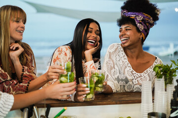 Multiracial happy friends cheering and drinking mojitos at beach party - Focus on center girl face