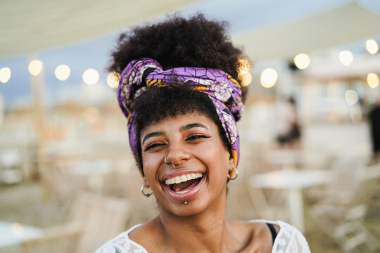 Bohemian african girl smiling on camera with beach bar on background - Focus on eyes