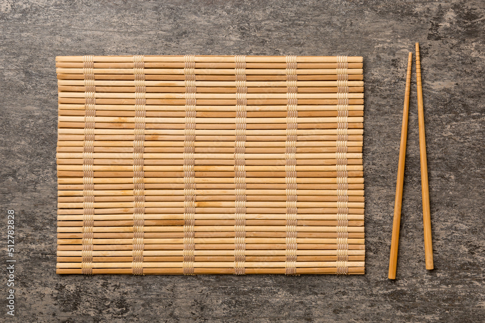 Wall mural Two chopsticks and bamboo mat on cement background. Top view, copy space