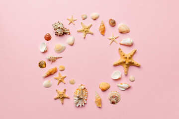 Summer time concept on colored background. Seashells from ocean shore in the shape of frame separated with space for text top view