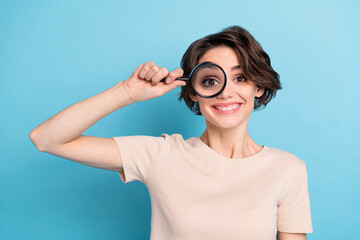 Photo of adorable cheerful young woman visit oculist check her eye vision with magnifier isolated...