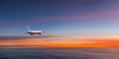Fototapeta na wymiar Commercial airplane jetliner flying above dramatic clouds in beautiful sunset light. Travel concept.